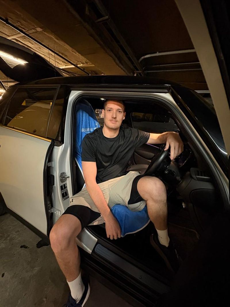 Frans, the founder, sitting in the driver's seat of his car in gym kit after training, on a Rawdog towel fitted over the seat.