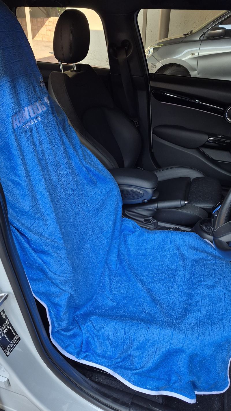 A Rawdog towel fitted to the driver's seat with the door open, showing how far the fabric hangs over the sides.
